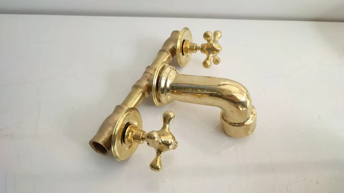 Unlacquered Brass Vintage Wall-mounted bathroom faucet with gold finish.